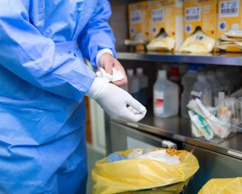 Male surgeon removing surgical gloves in operation theater at hospital